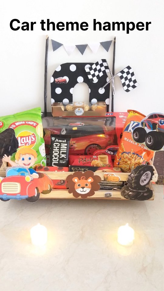Car-themed hamper arranged with toy cars, checkered flags, snacks, and a race-day backdrop